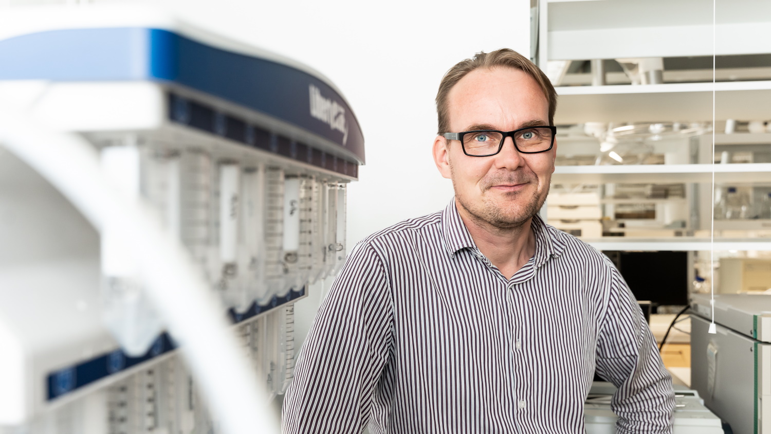 Professori Pasi Virta katsoo kameraan puolilähikuvassa, kemian laboratoriossa.